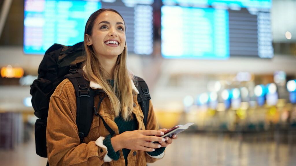 Seguros de viaje baratos - Mujer mochilera en el aeropuerto lista para su viaje