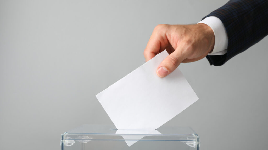 Mano poniendo su voto en una urna